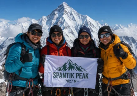 Four women mountaineers from Gilgit-Baltistan pose on the snow-covered summit of Spantik Peak, holding a Pakistani flag.
